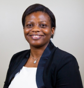 image is a headshot. It shows a woman smiling at the camera wearing a black blazer.
